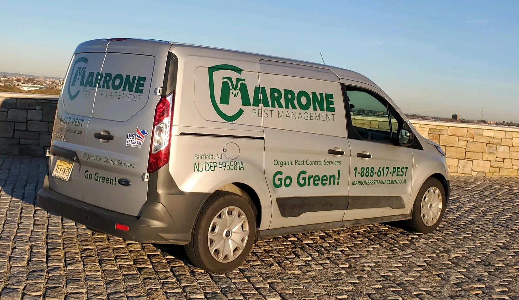 A Marrone Pest Management service van in evening light, its logo, Go Green message and 1-888-617-PEST number visible