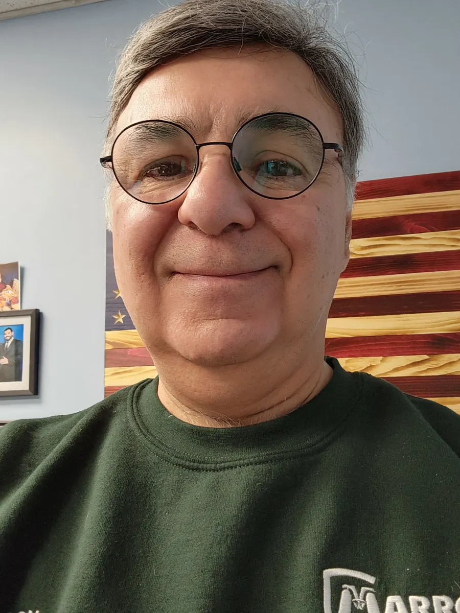 Ron Marrone, President, in a Marrone Pest Management sweatshirt in front of a wooden American flag